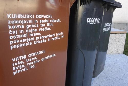 Rjavi zabojnik z napisom od blizu, v ozadju črna zabojnika.