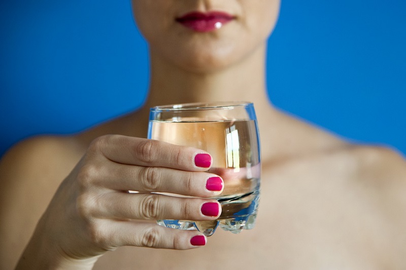 Ženska drži kozarec z vodo v roki.