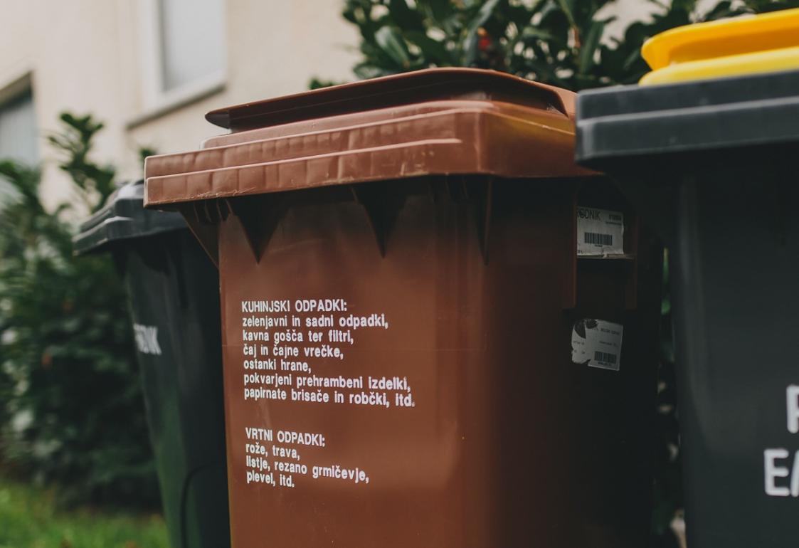 Rjavi zabojnik z napisom od blizu, v ozadju črna zabojnika.